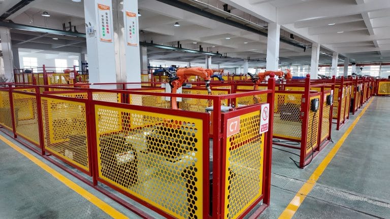 Rows of automated robotic cells with yellow and red safety enclosures streamline efficient, high-precision manufacturing